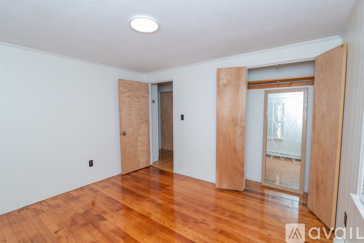 A room with wooden floors and a door on the left side.