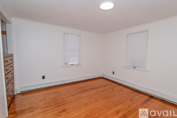 A room with wooden floors and two windows.