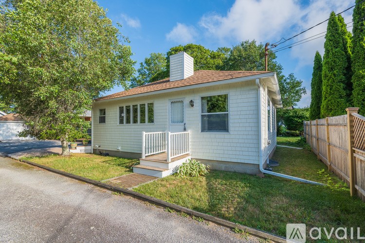 A small white house with a brown roof and a porch.