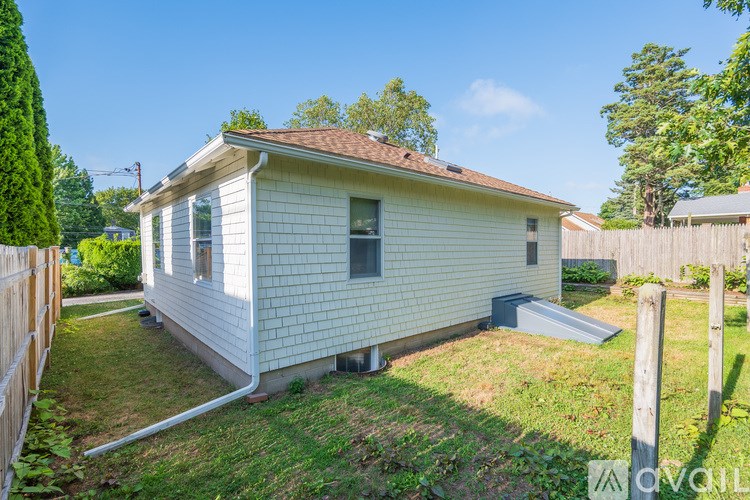A small white house with a brown roof and a grey garage door.