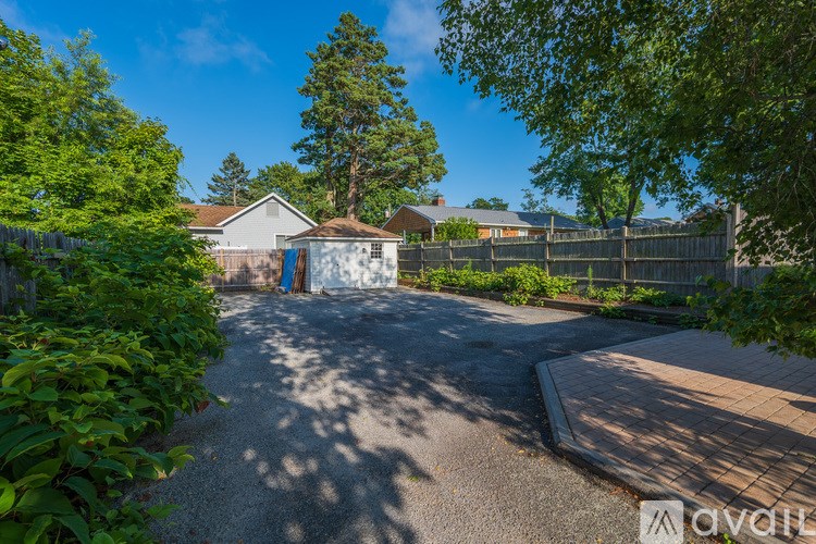 A sunny day in a residential area with a house, trees, and a driveway.