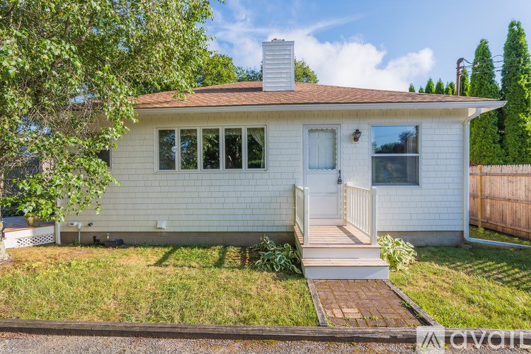 A white house with a brown roof and a white fence.