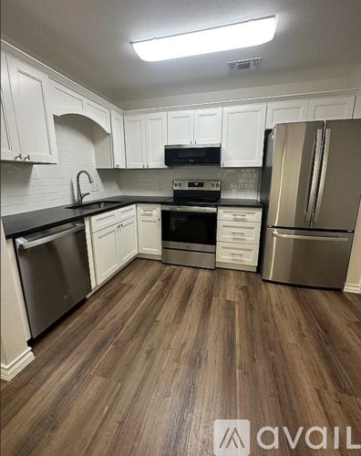 A kitchen with white cabinets and a wooden floor.