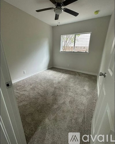A room with a ceiling fan and a window with blinds.