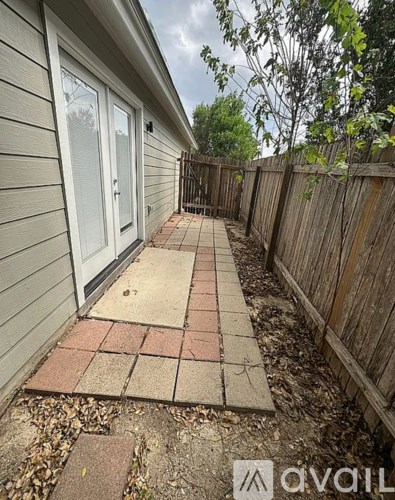 A backyard with a brick pathway leading to a house.