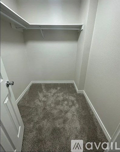 A hallway with a carpeted floor and a door on the left.