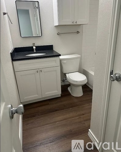 A bathroom with a sink, toilet and cabinets.