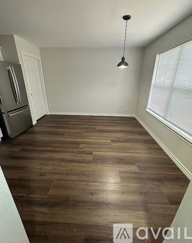 A room with wooden flooring and a hanging light fixture.