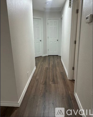 A long hallway with wood floors and white walls.