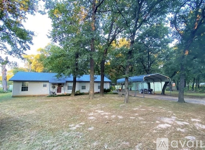 A house surrounded by trees in a grassy area.