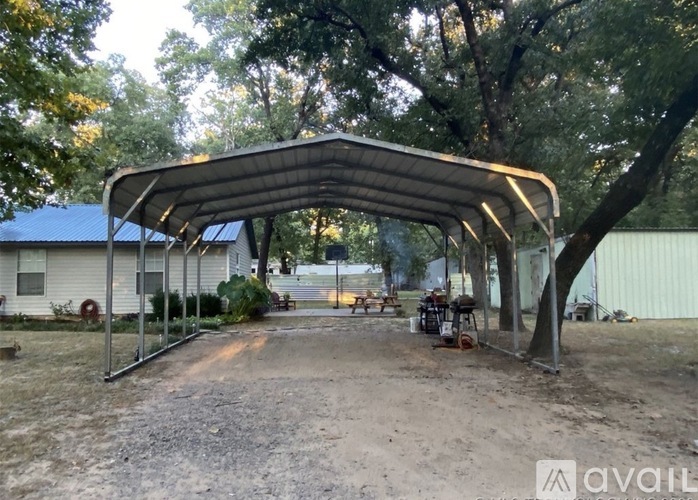 A covered patio area with a metal roof and a gravel ground.