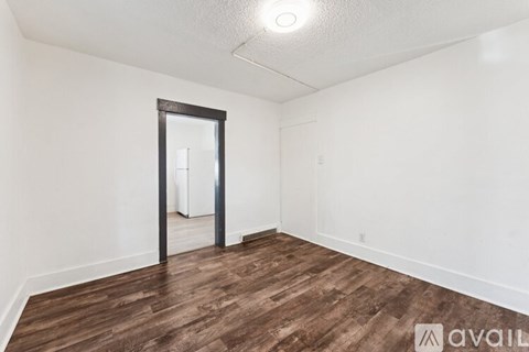 A room with a wooden floor and a doorway leading to another room.