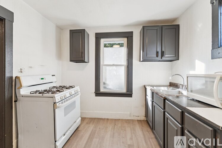A kitchen with a white stove top oven and a window with a black frame.