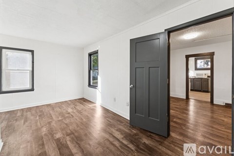 A room with a black door and wooden flooring.