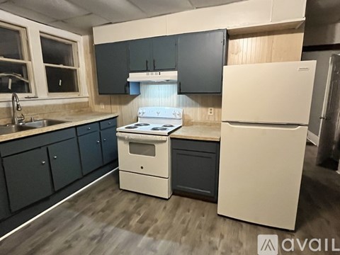 A kitchen with a white fridge, black cabinets, and a white stove top oven.