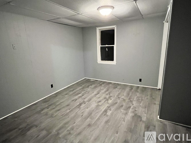 A room with a window and wooden flooring.