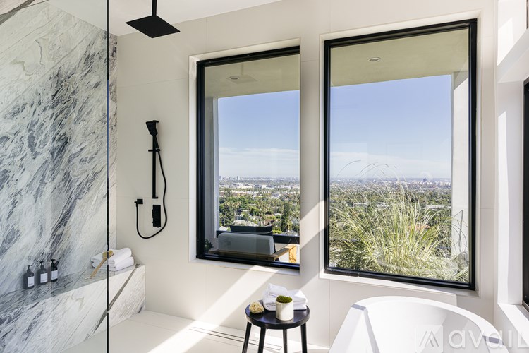 A bathroom with a marble tub and a window overlooking a cityscape.