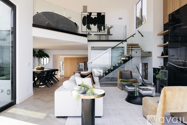 A modern living room with a glass staircase leading to the upper level.