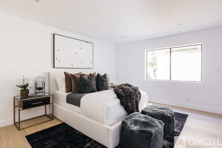 A modern bedroom with a large bed and a black and white artwork on the wall.