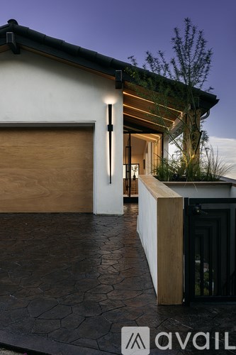 A modern house with a wooden door and a stone pathway leading to it.