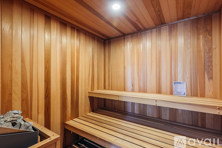 A wooden sauna with a bench and a container of stones.