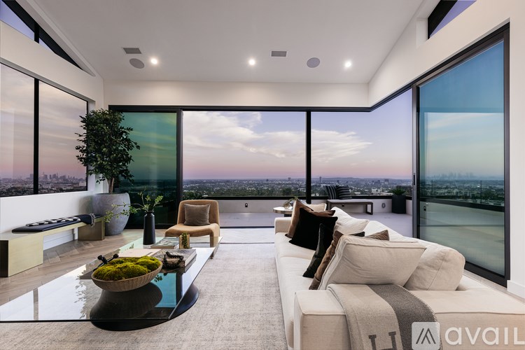 A modern living room with a view of the cityscape outside the large windows.