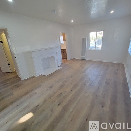 A spacious room with wooden flooring and a fireplace.