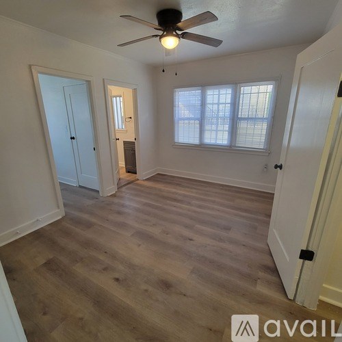 A room with a ceiling fan and wooden flooring.