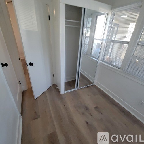 A room with a white door and a wooden floor.