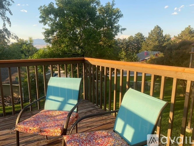 Two chairs on a deck with a mountain view in the background.