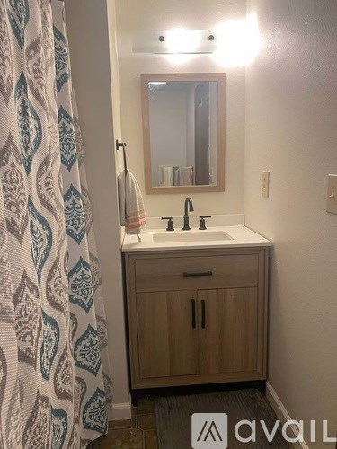 A bathroom with a sink, mirror, and cabinets.