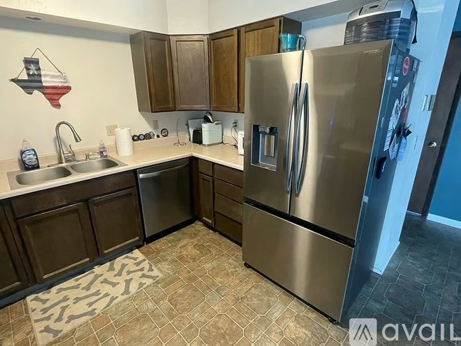 A kitchen with a refrigerator, sink, and cabinets.