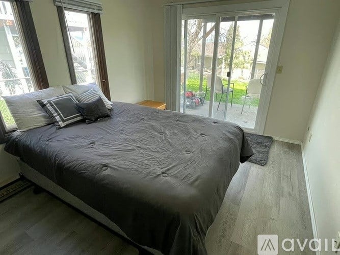 A bedroom with a large bed and sliding glass doors leading to a patio.