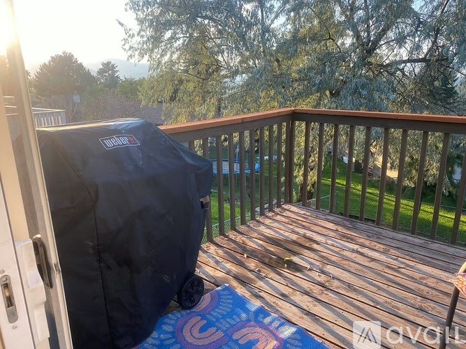 A black grill cover is on a wooden deck.