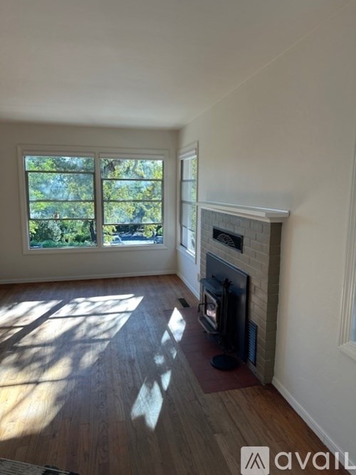 A room with a fireplace and a window overlooking trees.