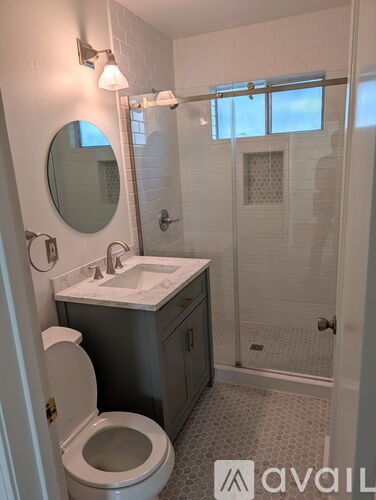 A bathroom with a toilet, sink, mirror and shower.