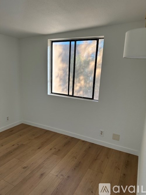 A room with a large window and wooden flooring.
