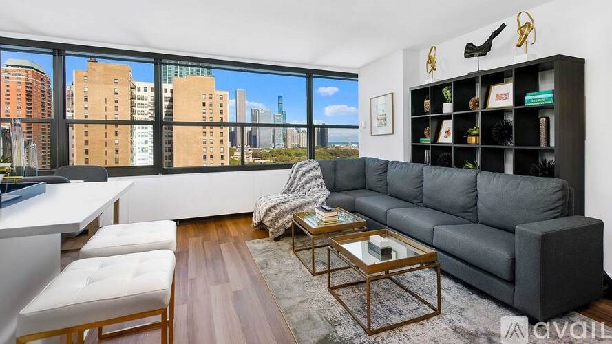 A living room with a grey sofa, a wooden coffee table, and a large window with a view of the city.