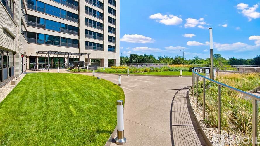 A grassy area in front of a building with a walkway and a metal railing.