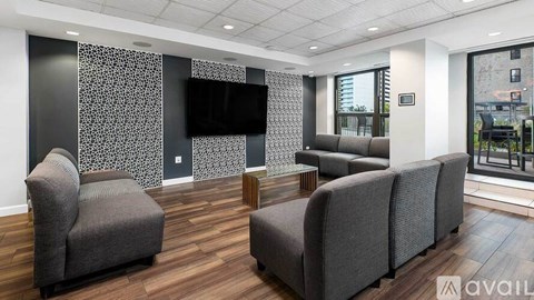 A living room with grey couches and a television mounted on the wall.