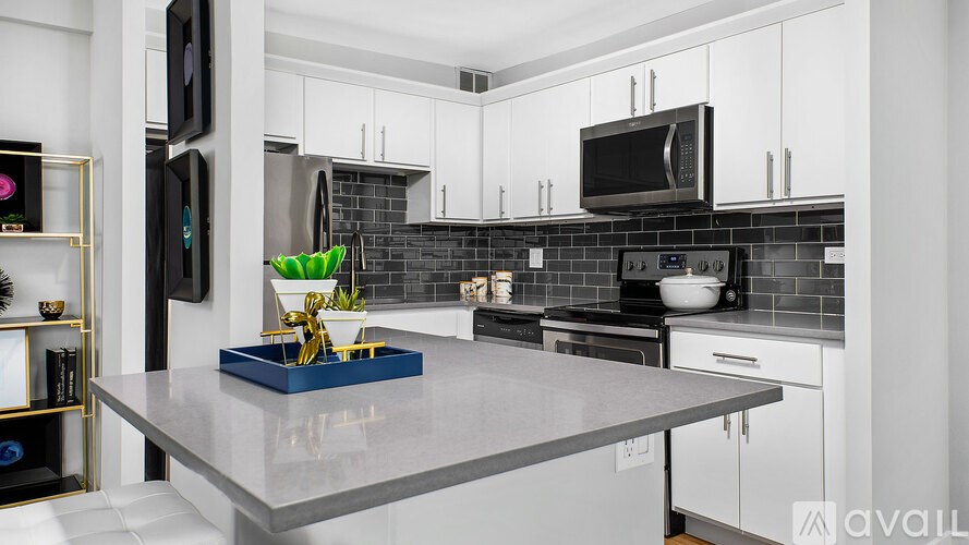A modern kitchen with a grey countertop and white cabinets.