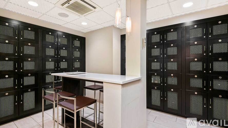 A room with a white table and brown chairs with a wall of black panels with windows.
