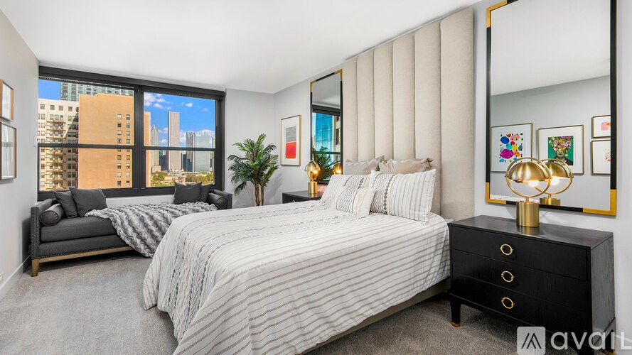 A bedroom with a large bed and a city view through the window.