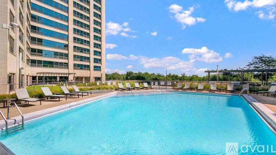 A swimming pool surrounded by lounge chairs and a tall building in the background.