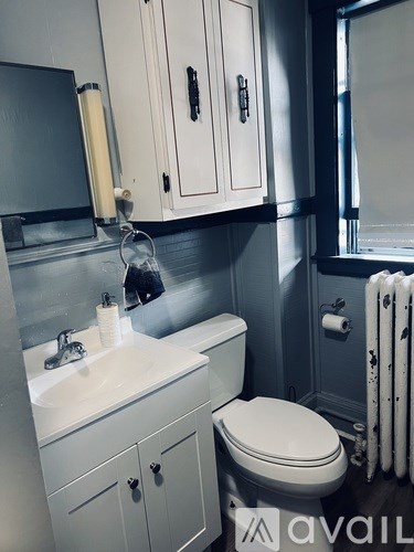 A bathroom with a toilet, sink, and cabinets.