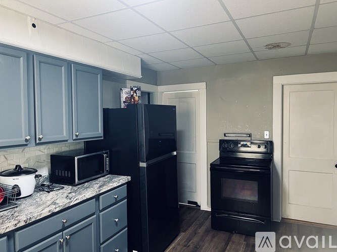 A kitchen with black appliances and grey cabinets.