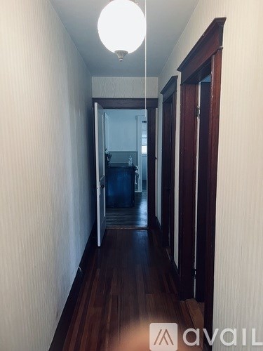 A long hallway with a light on the ceiling and a door at the end.
