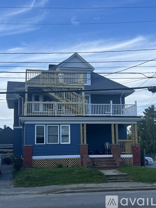 A blue house with a white balcony and a sign that says "avail" in front of it.