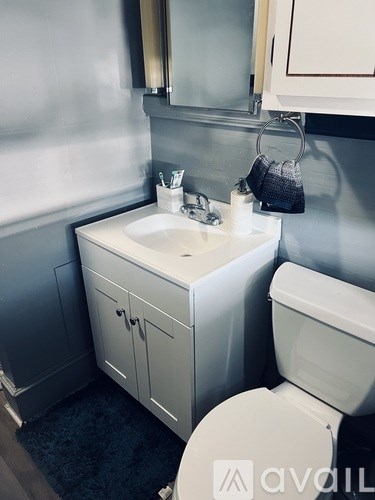 A bathroom with a toilet, sink, and mirror.