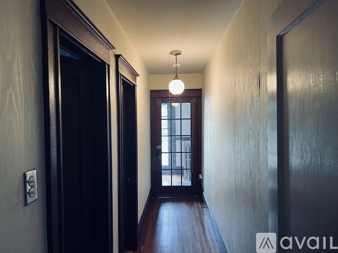 A long hallway with a light on and a door at the end.